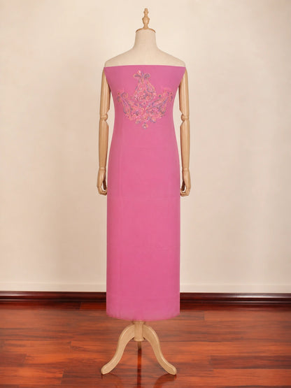 Pink evening gown with floral embroidery on a mannequin against a beige wall.