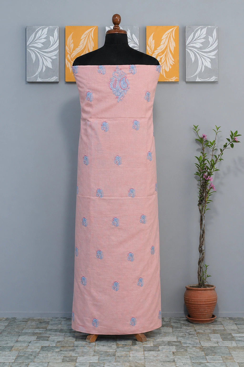 Lucknowi chikankari peach dress with floral patterns on a mannequin against a gray wall with decorative panels.