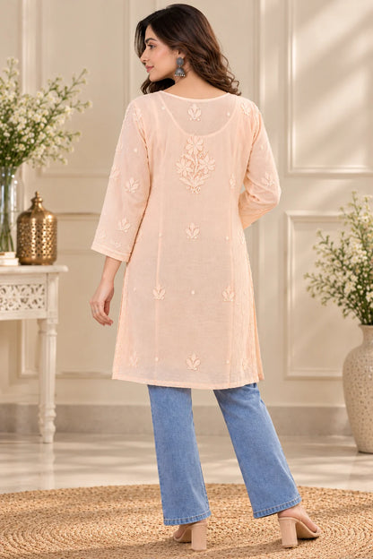 Woman wearing a lucknowi chikankari peach-colored kurta with white floral patterns