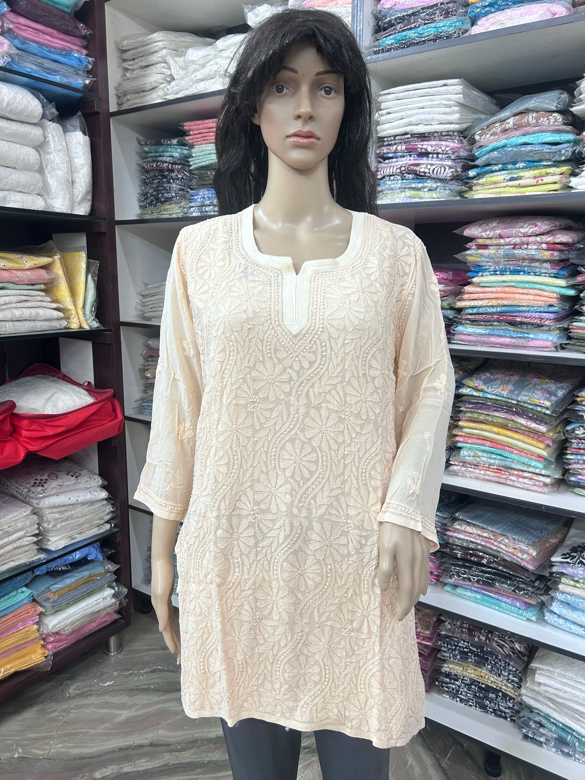 Woman wearing a lucknowi chikankari peach-colored kurta with white patterns on a white background