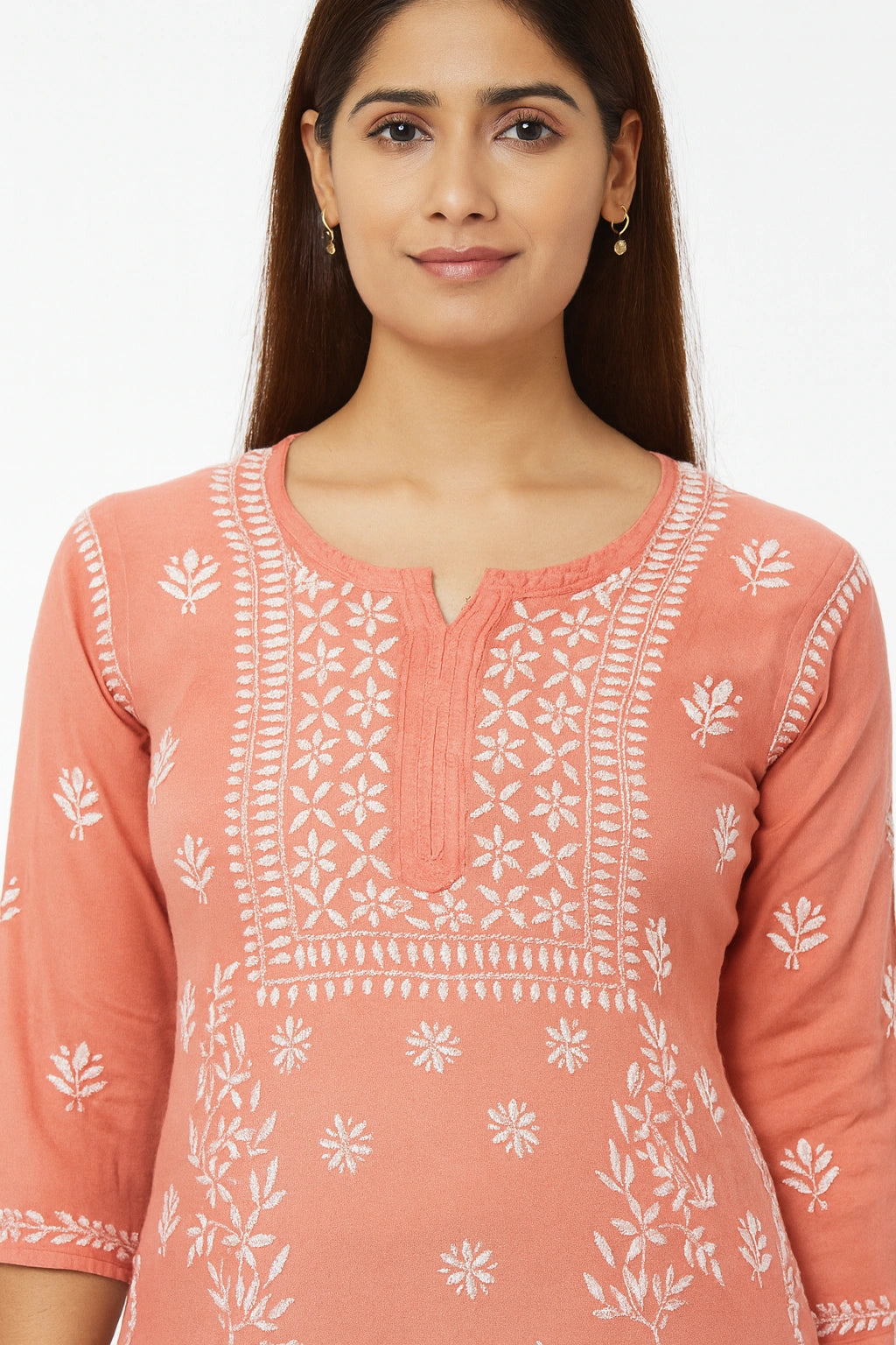 Woman wearing a lucknowi chikankari peach-colored kurta with white floral patterns on a plain background