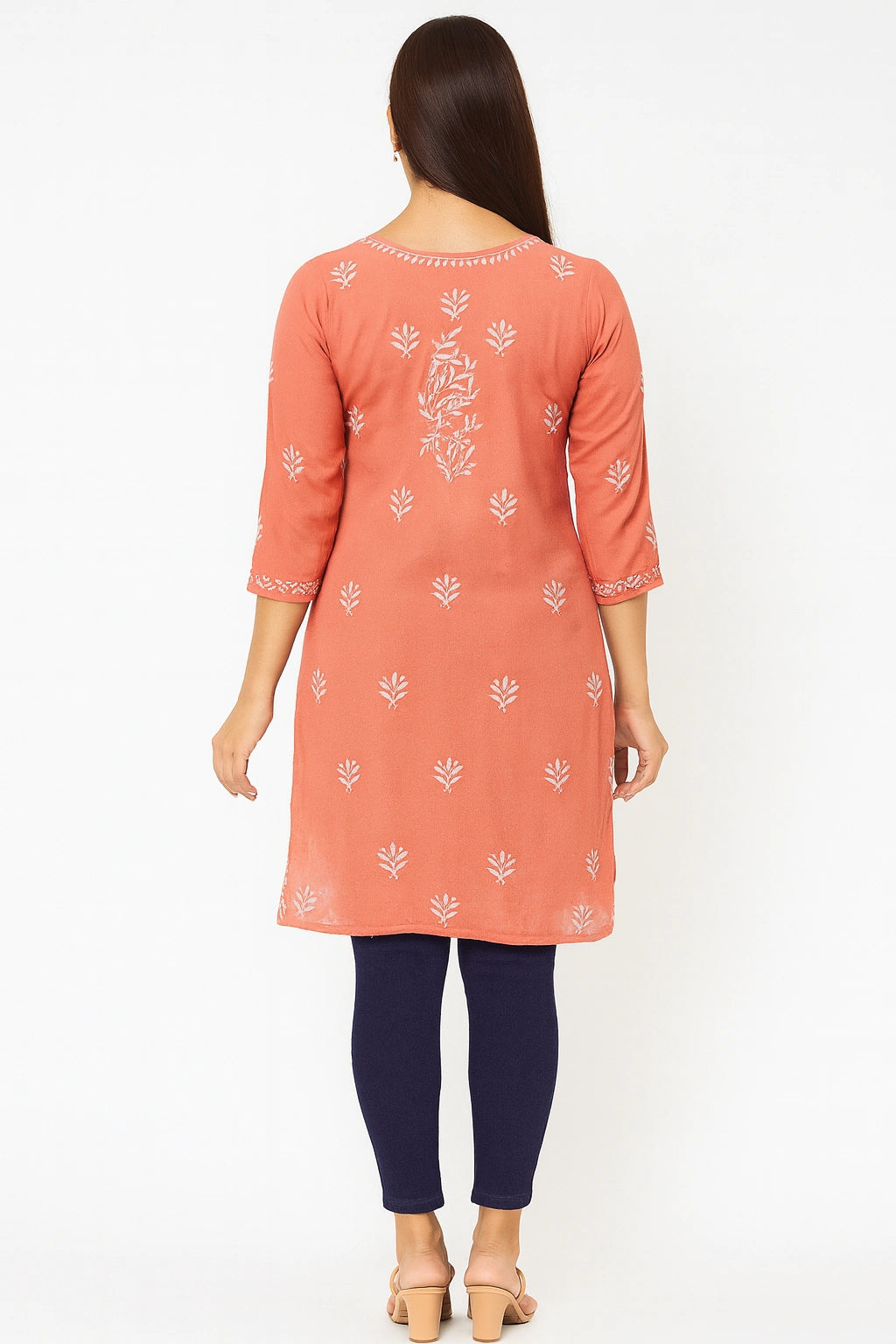 Woman wearing a lucknowi chikankari peach-colored kurta with white patterns on a white background