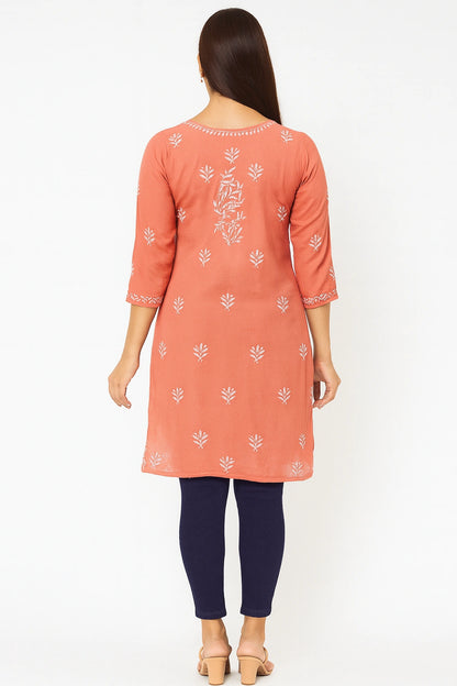 Woman wearing a lucknowi chikankari peach-colored kurta with white patterns on a white background