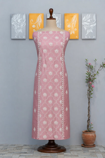 Lucknowi chikankari Pink dress with white floral pattern on a mannequin against a gray wall with decorative elements.