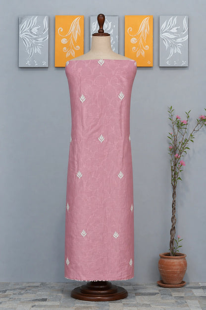 lucknowi chikankari Pink dress on a mannequin against a gray wall with decorative panels and a plant.