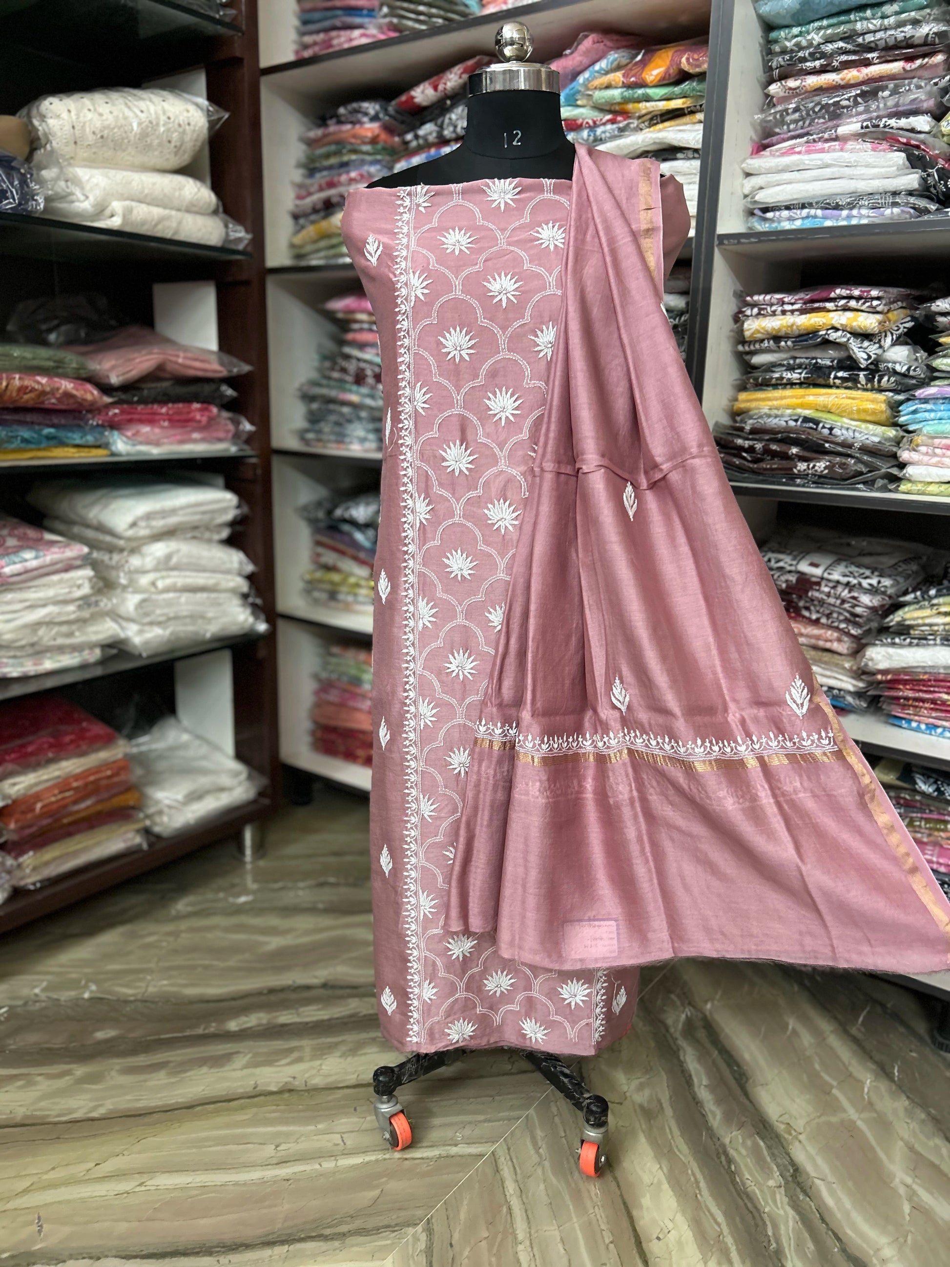 lucknowi chikankari Pink traditional outfit with white patterns on a mannequin in a fabric store.