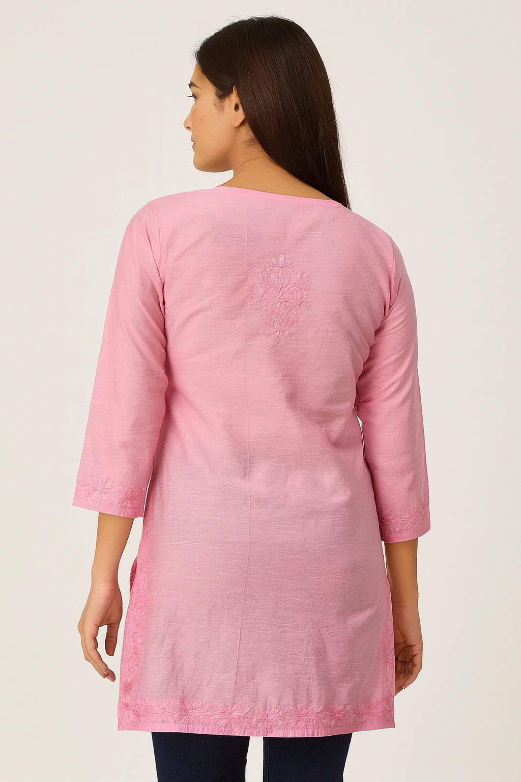 Woman wearing a lucknowi chikankari pink kurta with intricate designs on a plain background