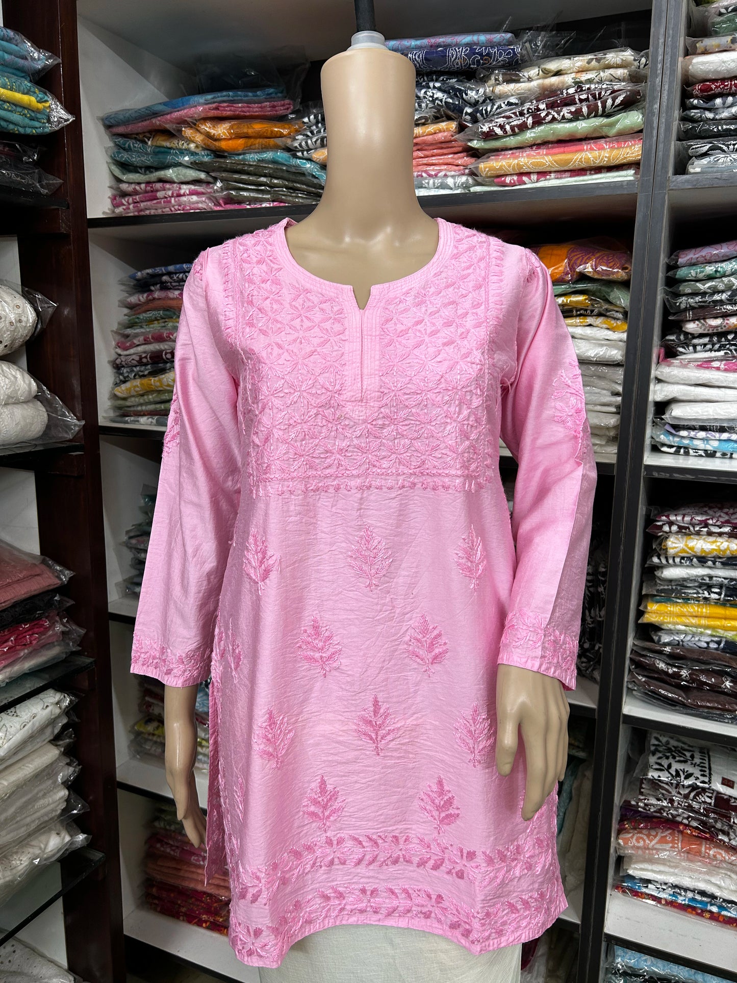 Mannequin wearing a pink embroidered dress in a fabric store.