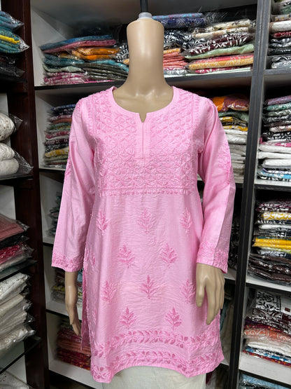 Mannequin wearing a pink embroidered dress in a fabric store.