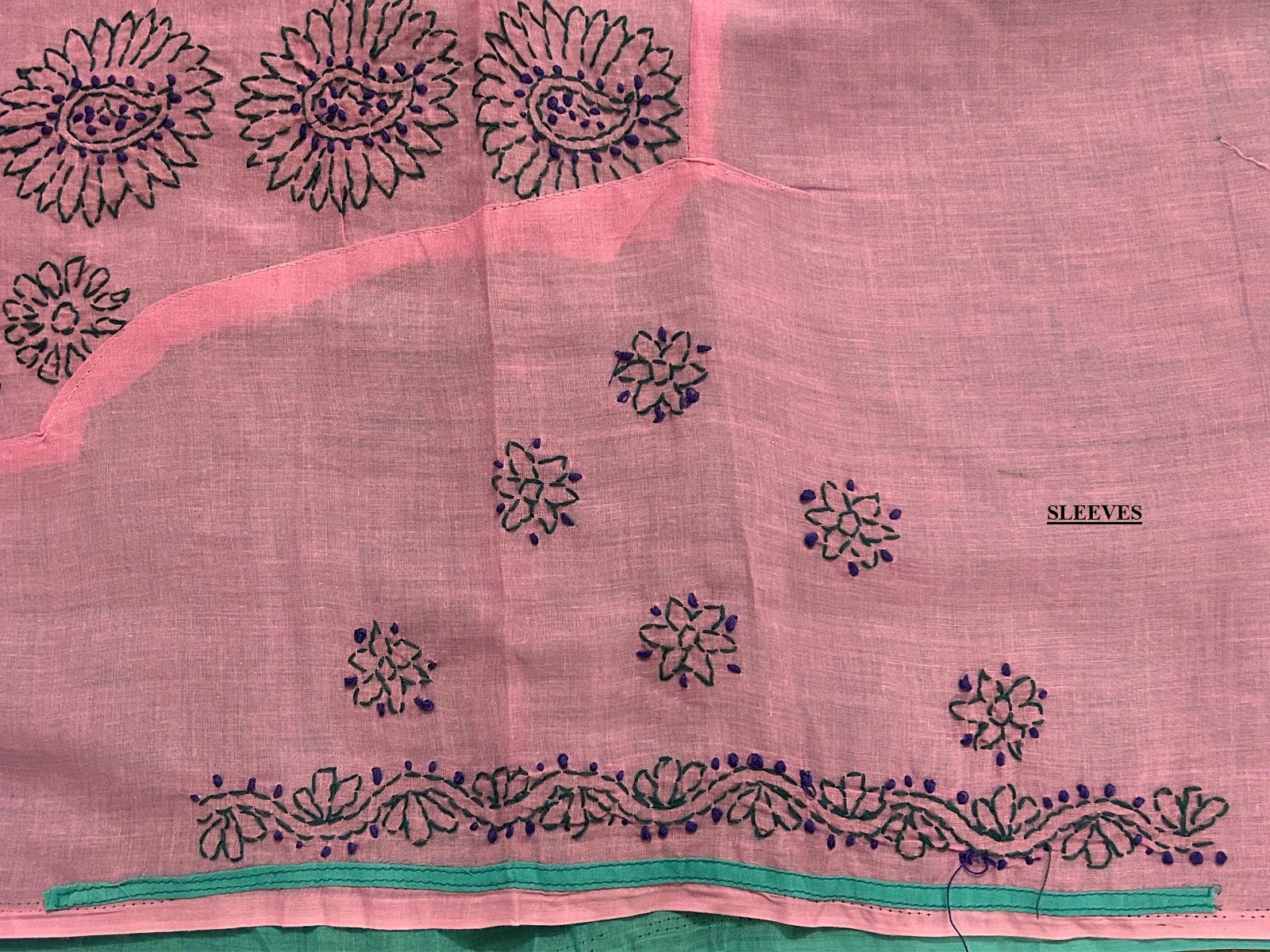 Pink fabric with black floral embroidery and green trim