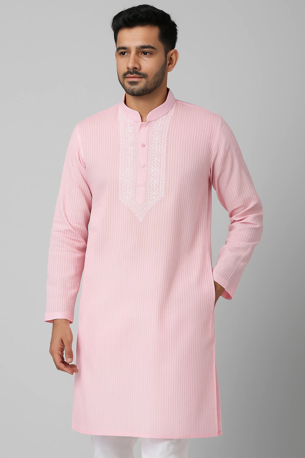 Man wearing a lucknowi chikankari light pink kurta with a plain background