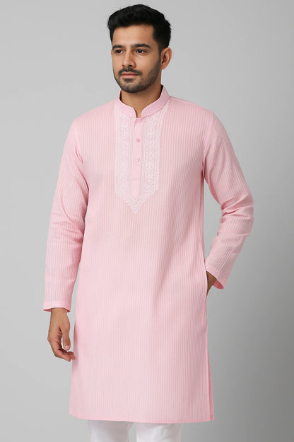 Man wearing a lucknowi chikankari light pink kurta with a plain background