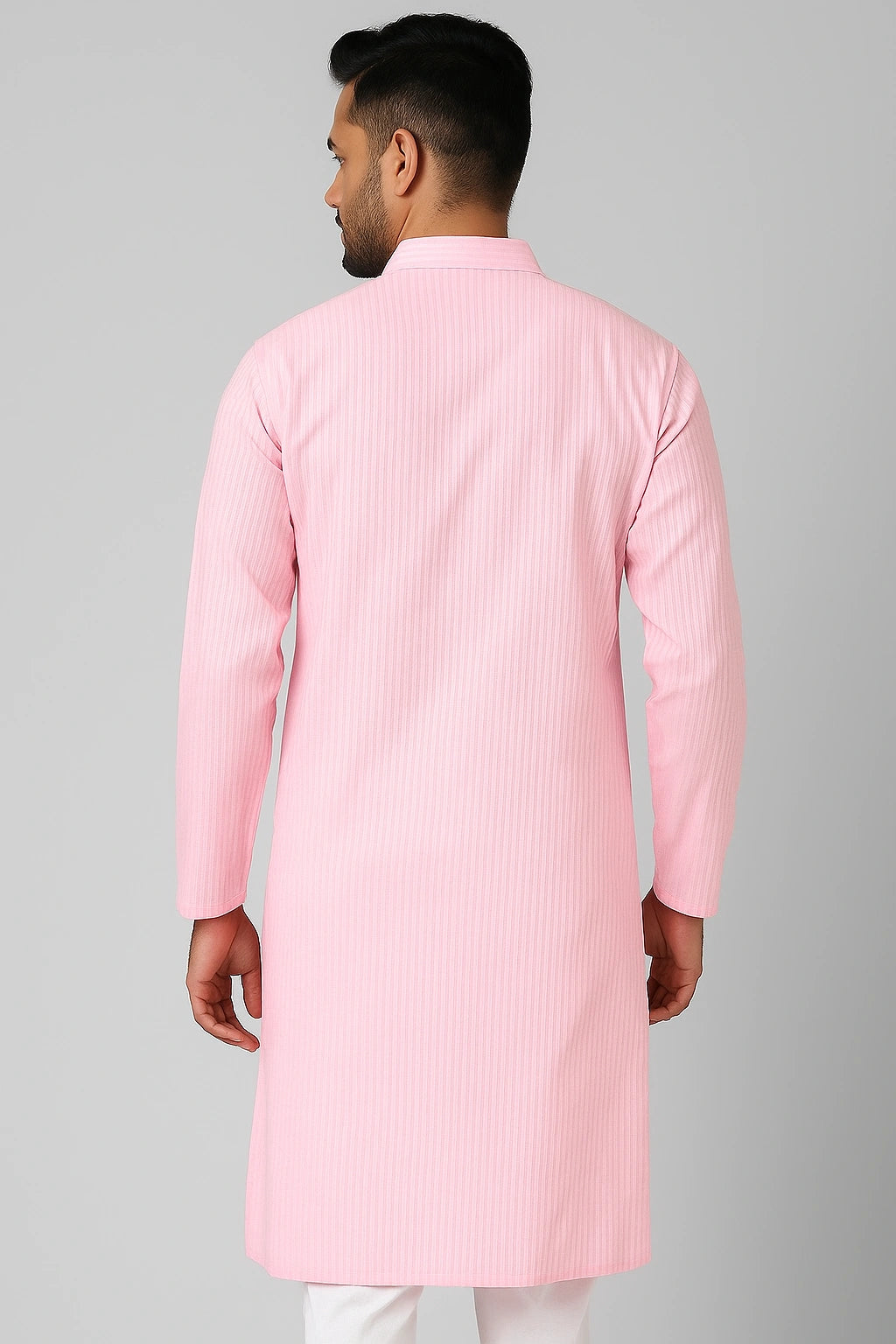 Man wearing a lucknowi chikankari pink kurta with white pants on a gray background