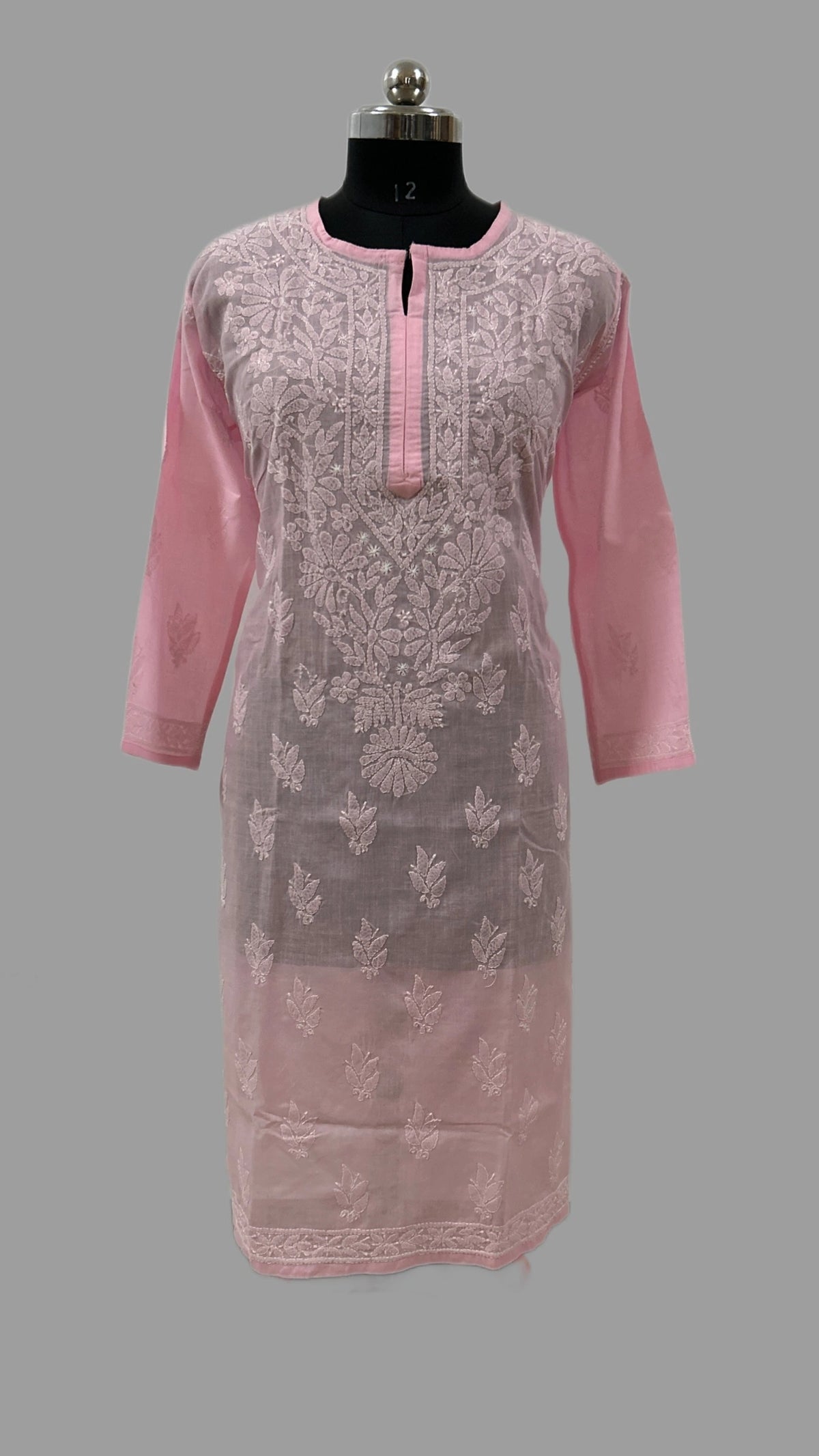 A pink embroidered kurta displayed on a black dress form mannequin against a solid gray background. The kurta features a sheer floral lace overlay over a solid pink inner fabric, with a pink buttoned placket and matching pink sleeves.