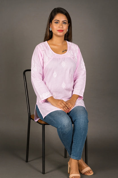 lucknowi chikankari Woman sitting on a chair wearing a light pink top and blue jeans against a gray background