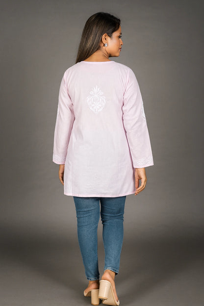 lucknowi chikankari Woman wearing a light pink long-sleeve top with a white design on the back, standing against a gray background.