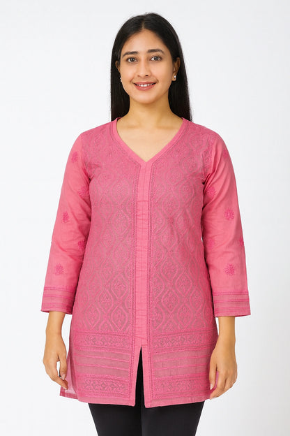 Woman wearing a pink embroidered top on a white background