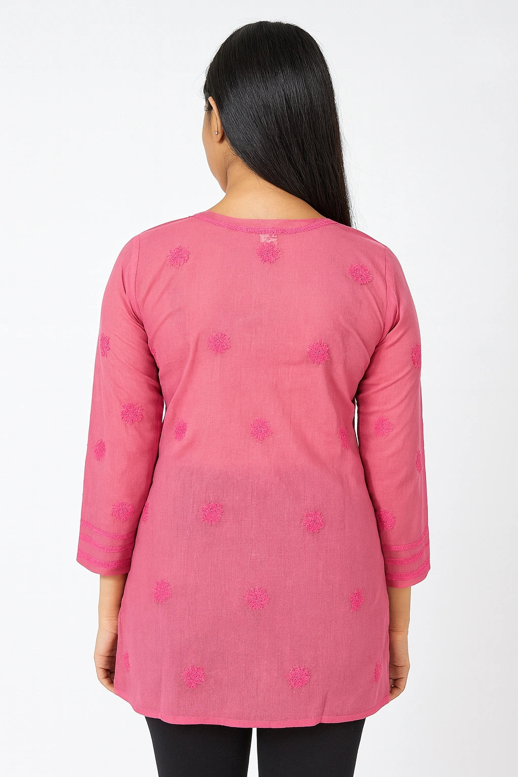 Woman wearing a pink embroidered top on a white background