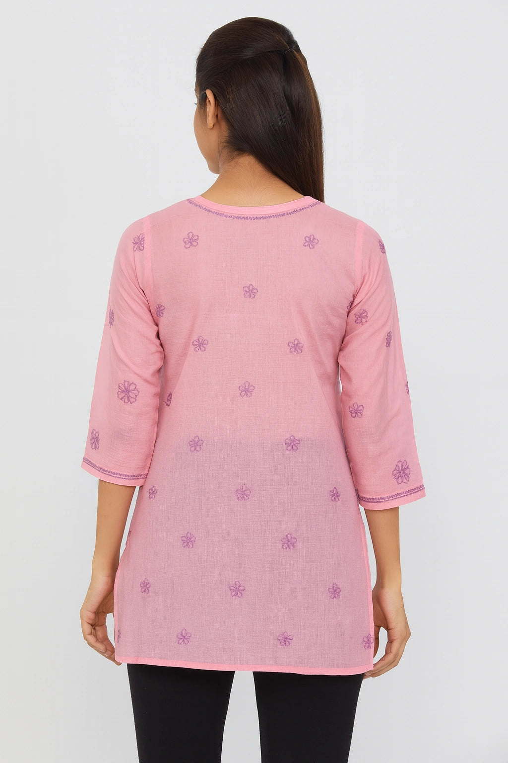 Pink embroidered top worn by a person on a white background