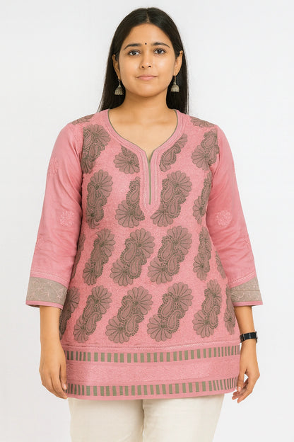 Woman wearing a lucknowi chikankari pink and green patterned kurta with white pants on a white background