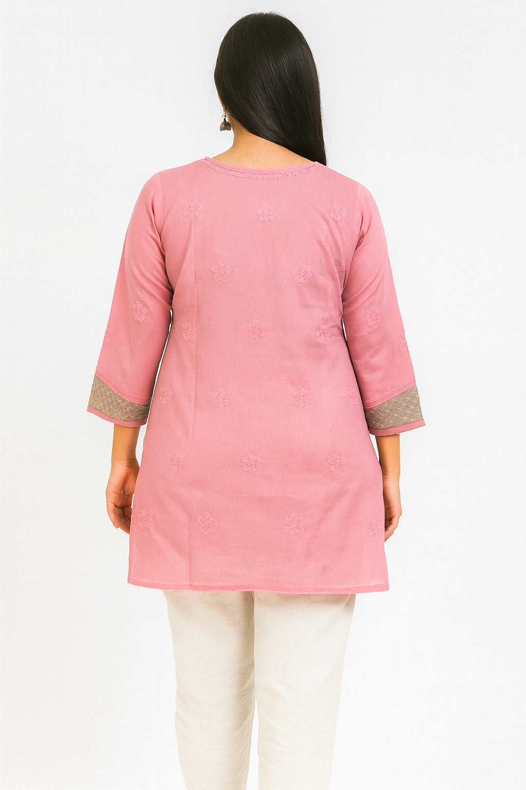 Woman wearing a lucknowi chikankari pink and green patterned kurta with white pants on a white background