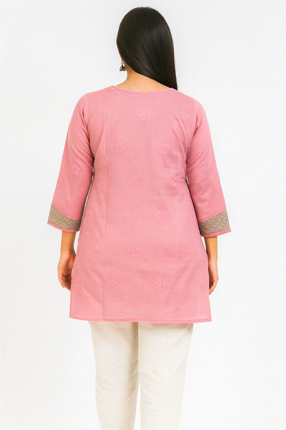 Woman wearing a lucknowi chikankari pink and green patterned kurta with white pants on a white background