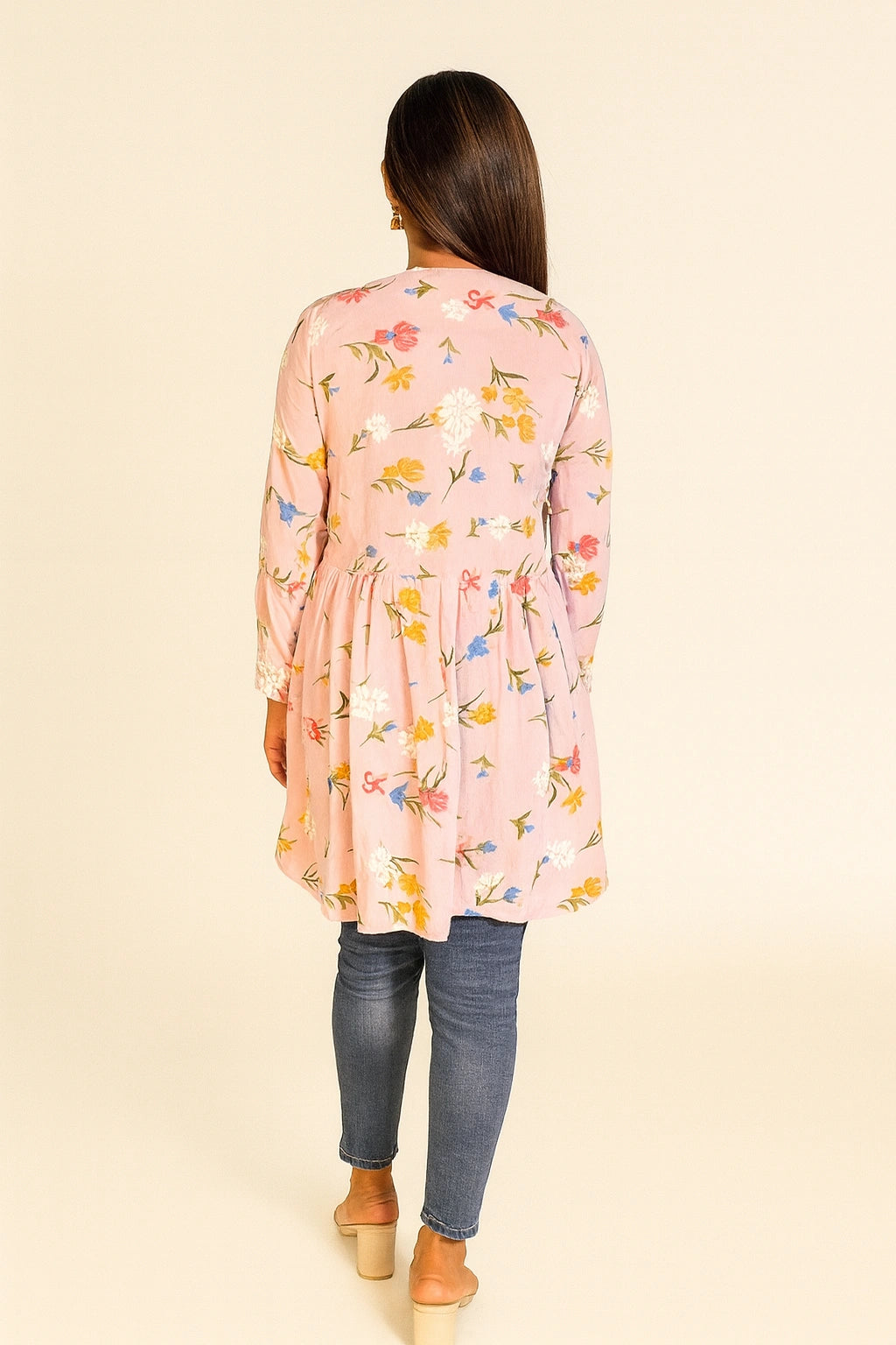 lucknowi chikankariWoman wearing a pink floral dress with blue jeans on a beige background