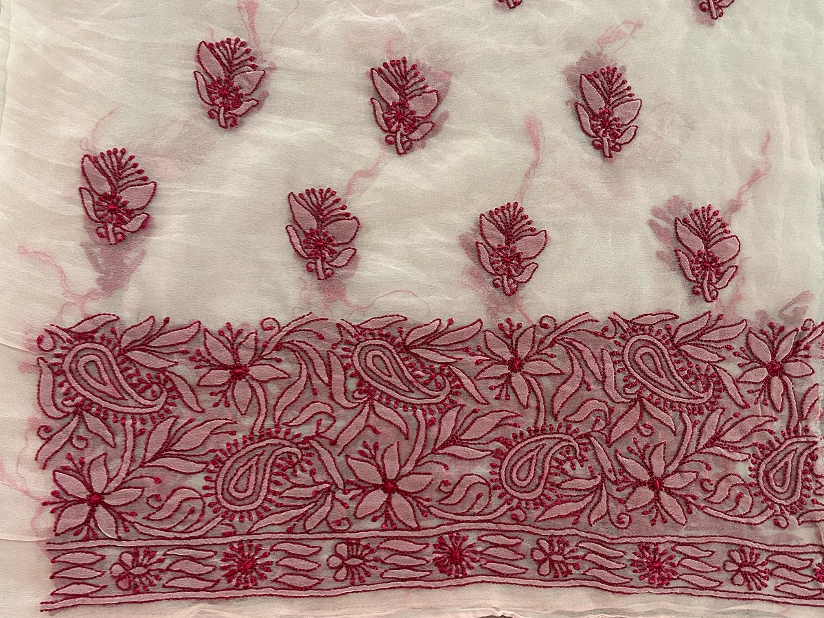 Embroidered fabric with red floral and paisley patterns on a white background