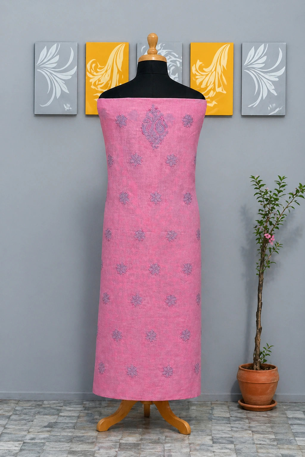 Pink dress with floral patterns on a mannequin against a gray wall with decorative panels.