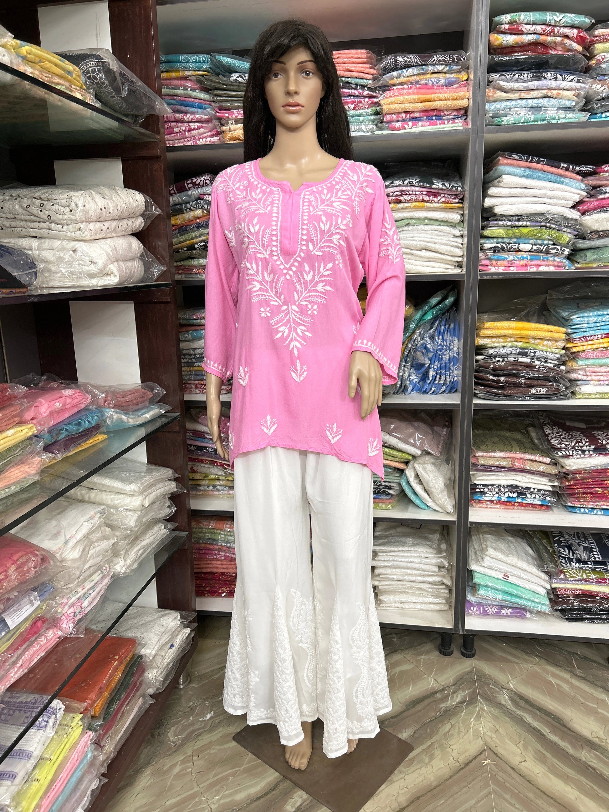 Mannequin wearing a lucknowi chikankari pink top and white pants in a fabric store