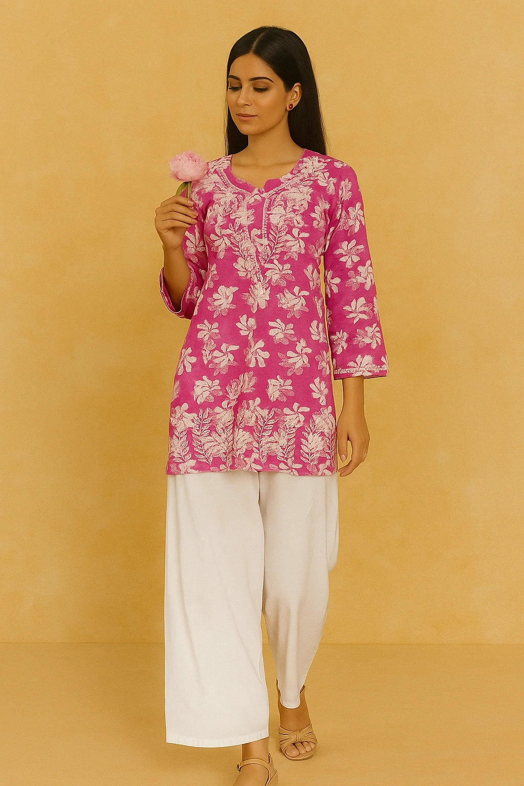 lucknowi chikankari Woman wearing a pink floral top and white pants against a beige background