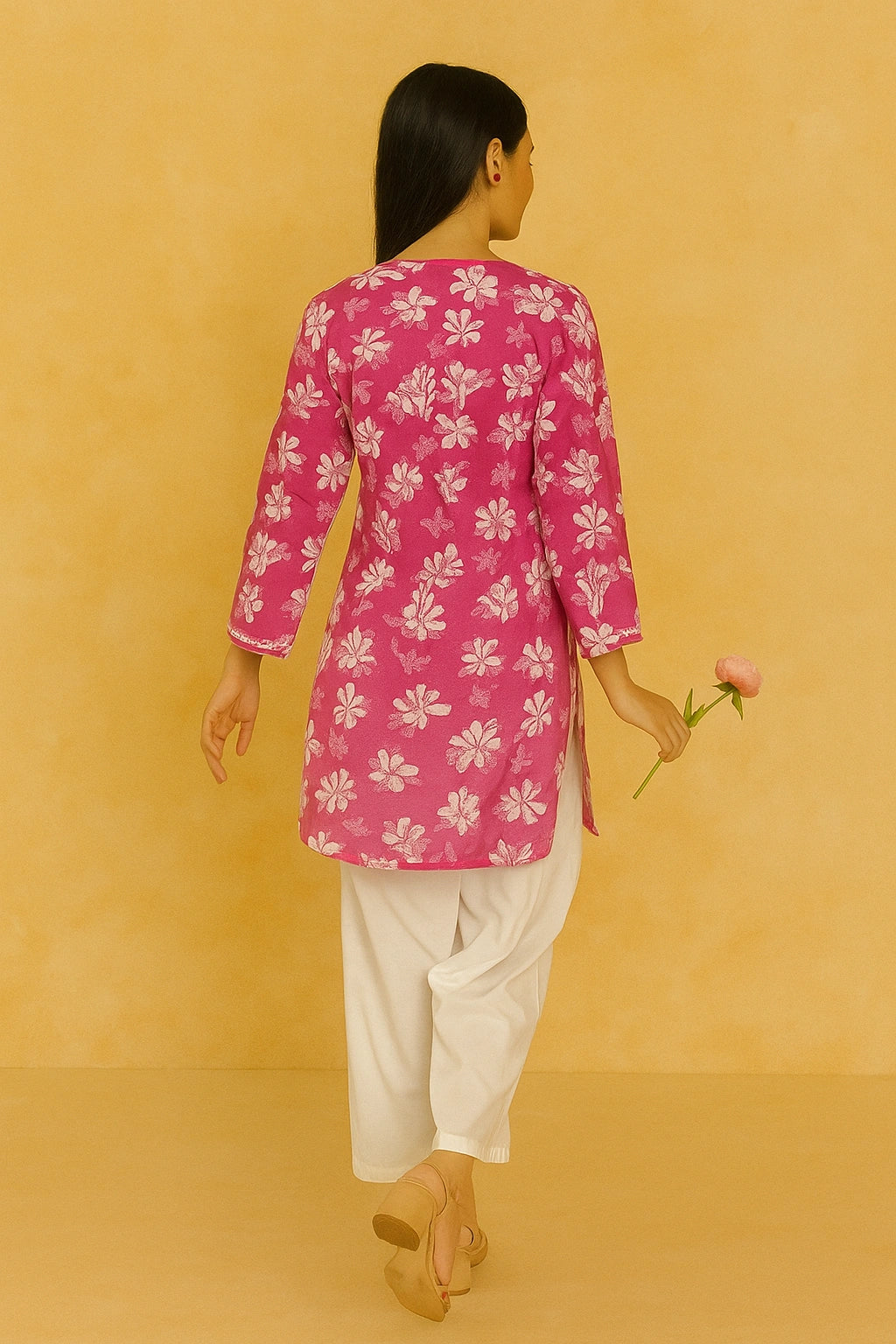 lucknowi chikankari Woman wearing a pink floral top and white pants against a beige background
