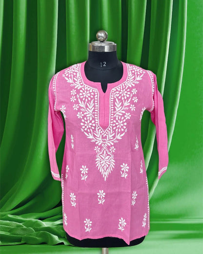 Pink embroidered dress on a mannequin against a green curtain background