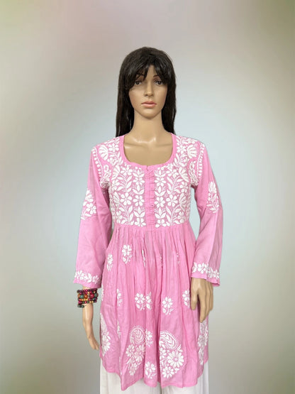 Mannequin wearing a pink dress with white floral embroidery on a plain background