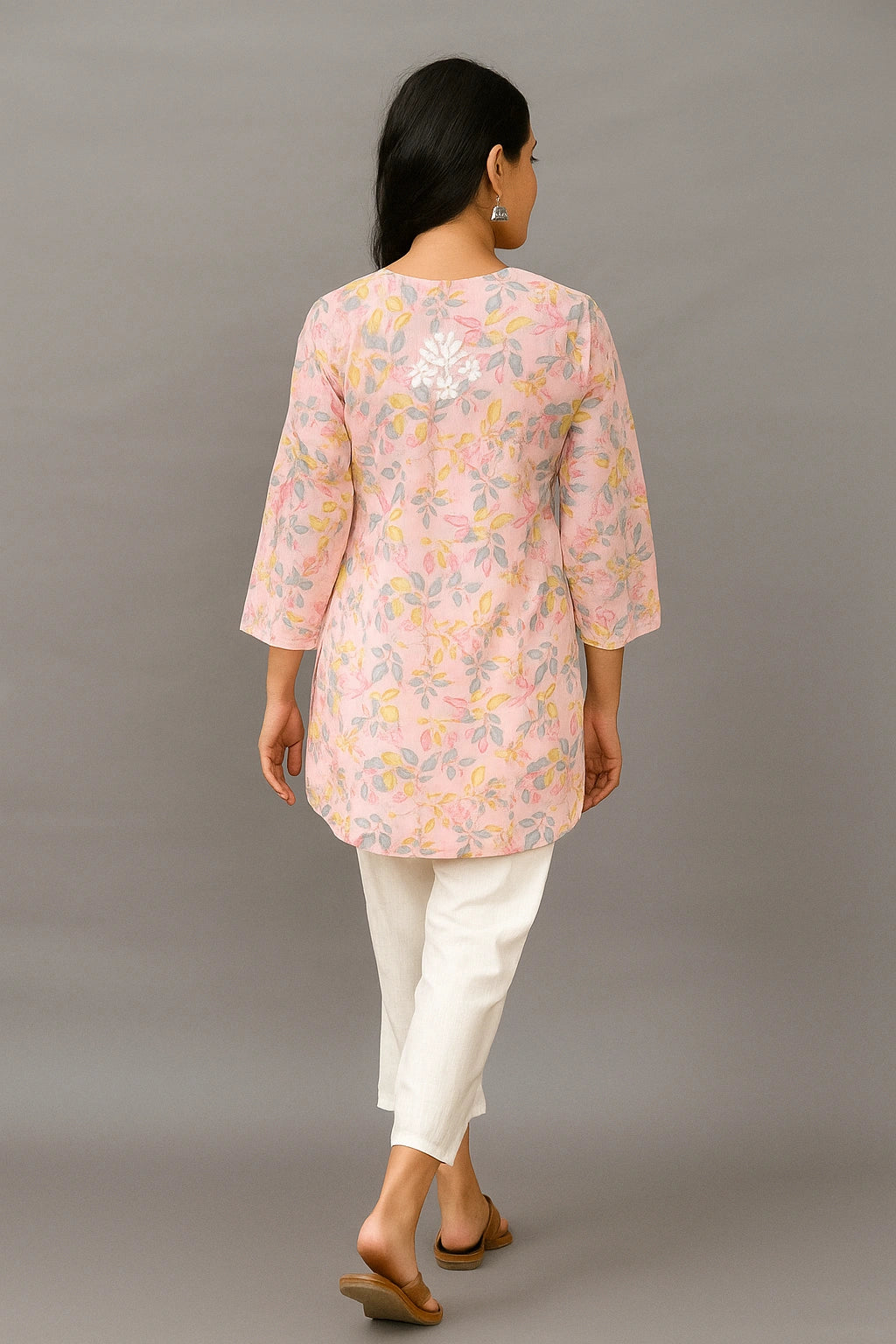 lucknowi chikankari Woman wearing a pink floral blouse and white pants against a gray background