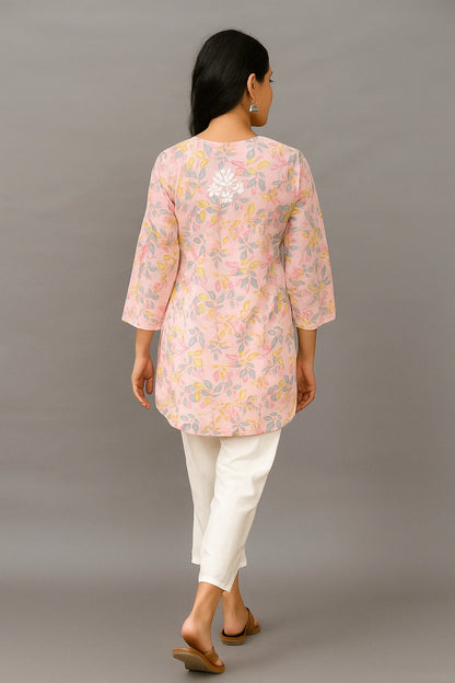 lucknowi chikankari Woman wearing a pink floral blouse and white pants against a gray background