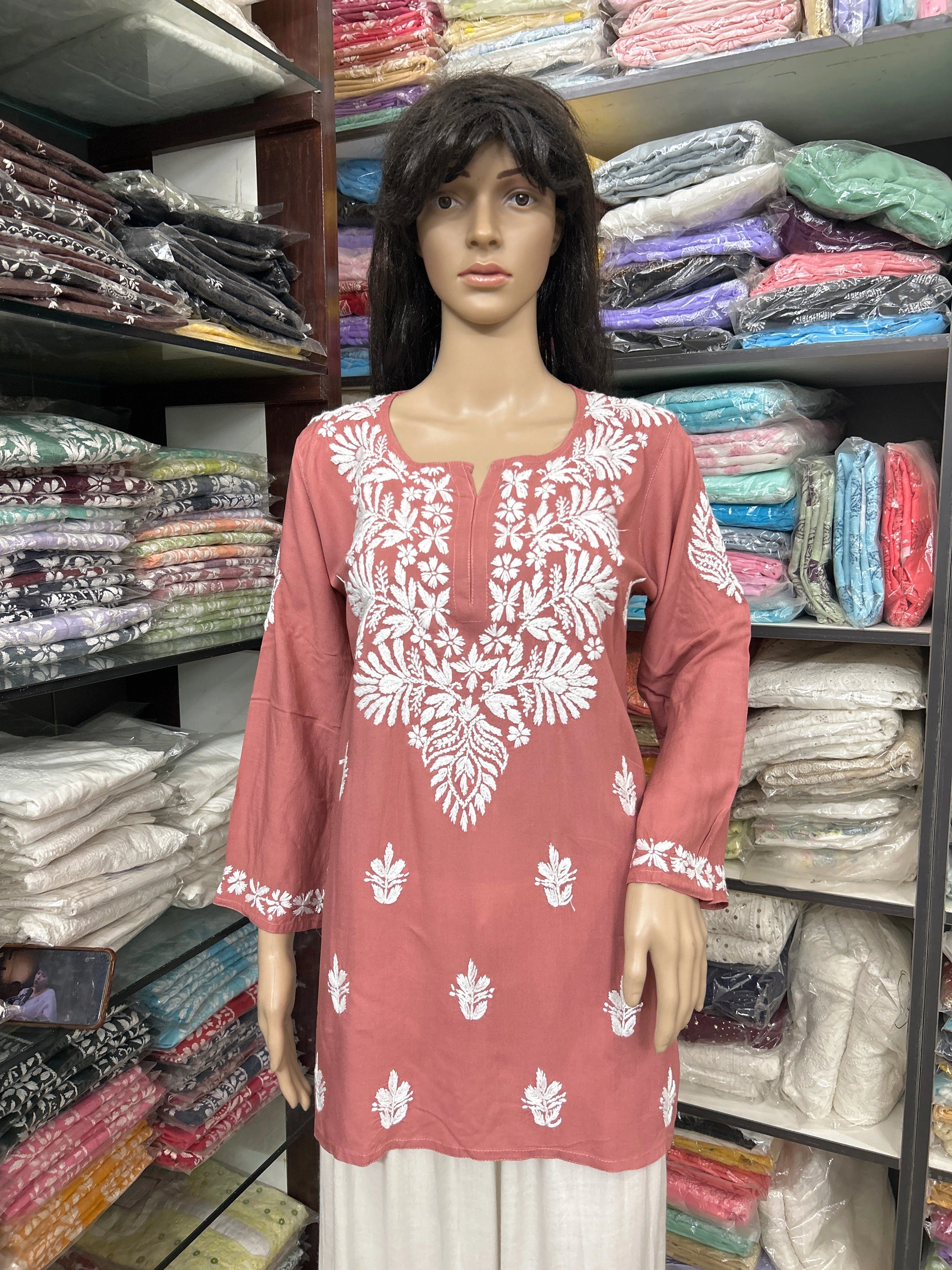 Mannequin wearing a pink embroidered top in a fabric store