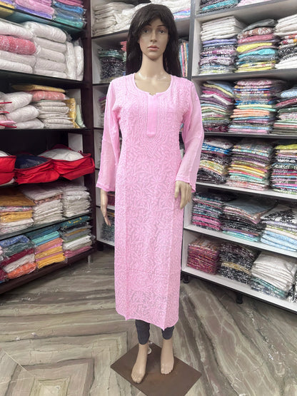 lucknowi chikankari A pink long-sleeve kurta displayed on a female mannequin in a clothing store, with shelves of folded fabrics in the background.