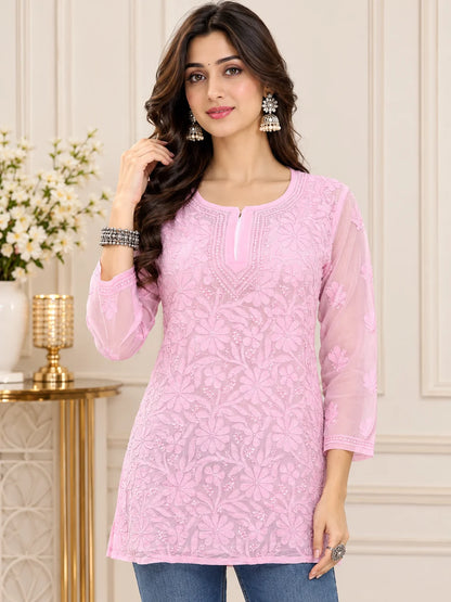 Woman wearing a lucknowi chikankari pink kurta with white floral patterns 