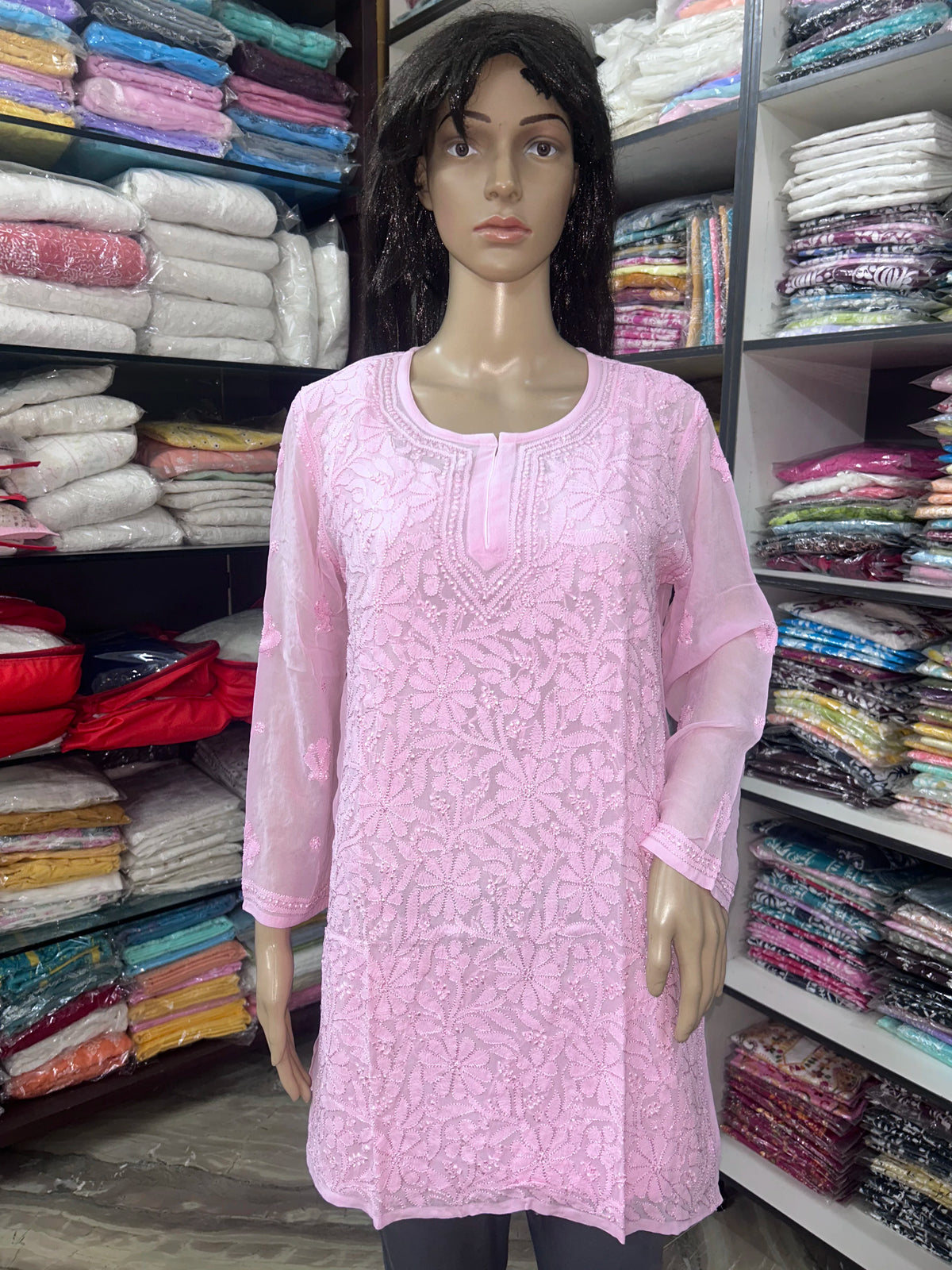 Woman wearing a lucknowi chikankari pink-colored kurta with white patterns on a white background