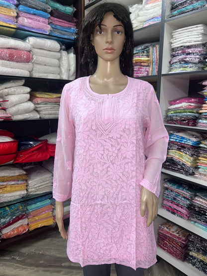 Woman wearing a lucknowi chikankari pink-colored kurta with white patterns on a white background