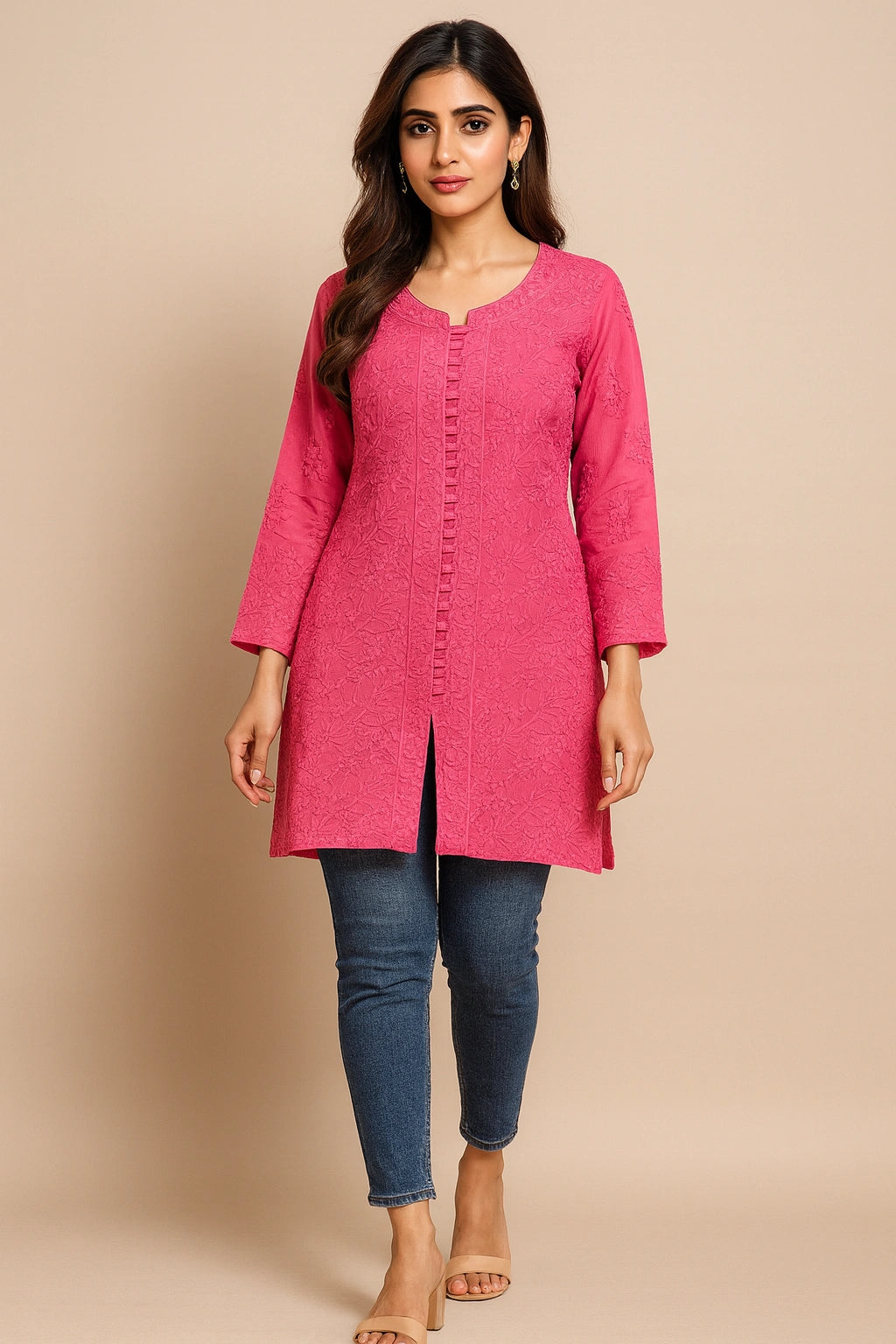 Woman wearing a lucknowi chikankari pink kurta with blue jeans on a beige background