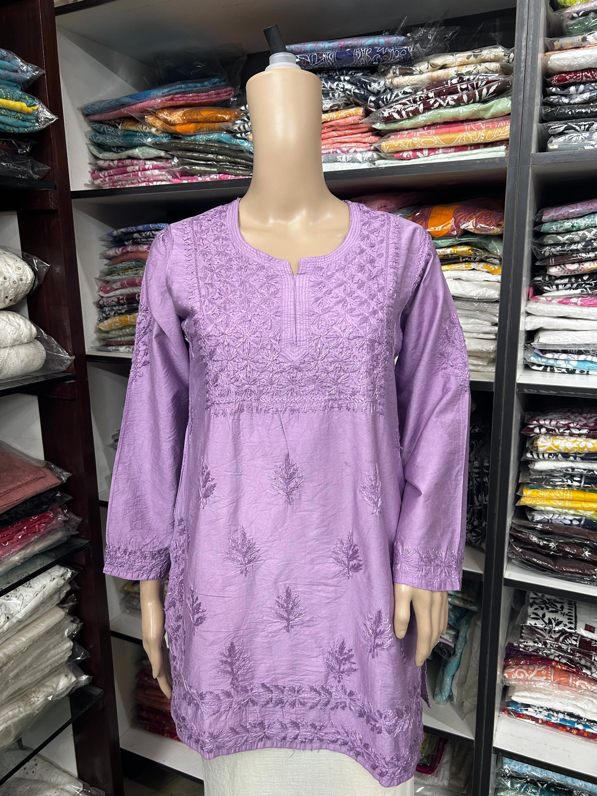 Purple embroidered dress on a mannequin in a fabric store.