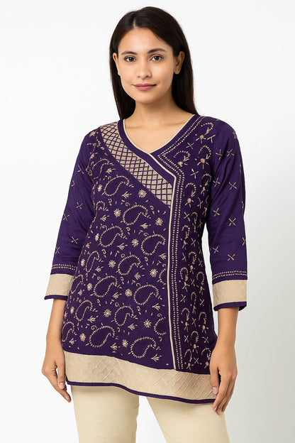 Woman wearing a lucknowi chikankari purple patterned top with beige pants on a white background
