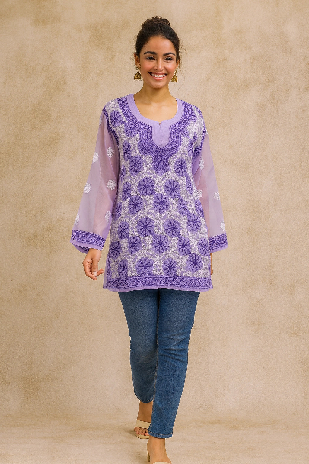 Woman wearing a purple embroidered top and blue pants against a beige background