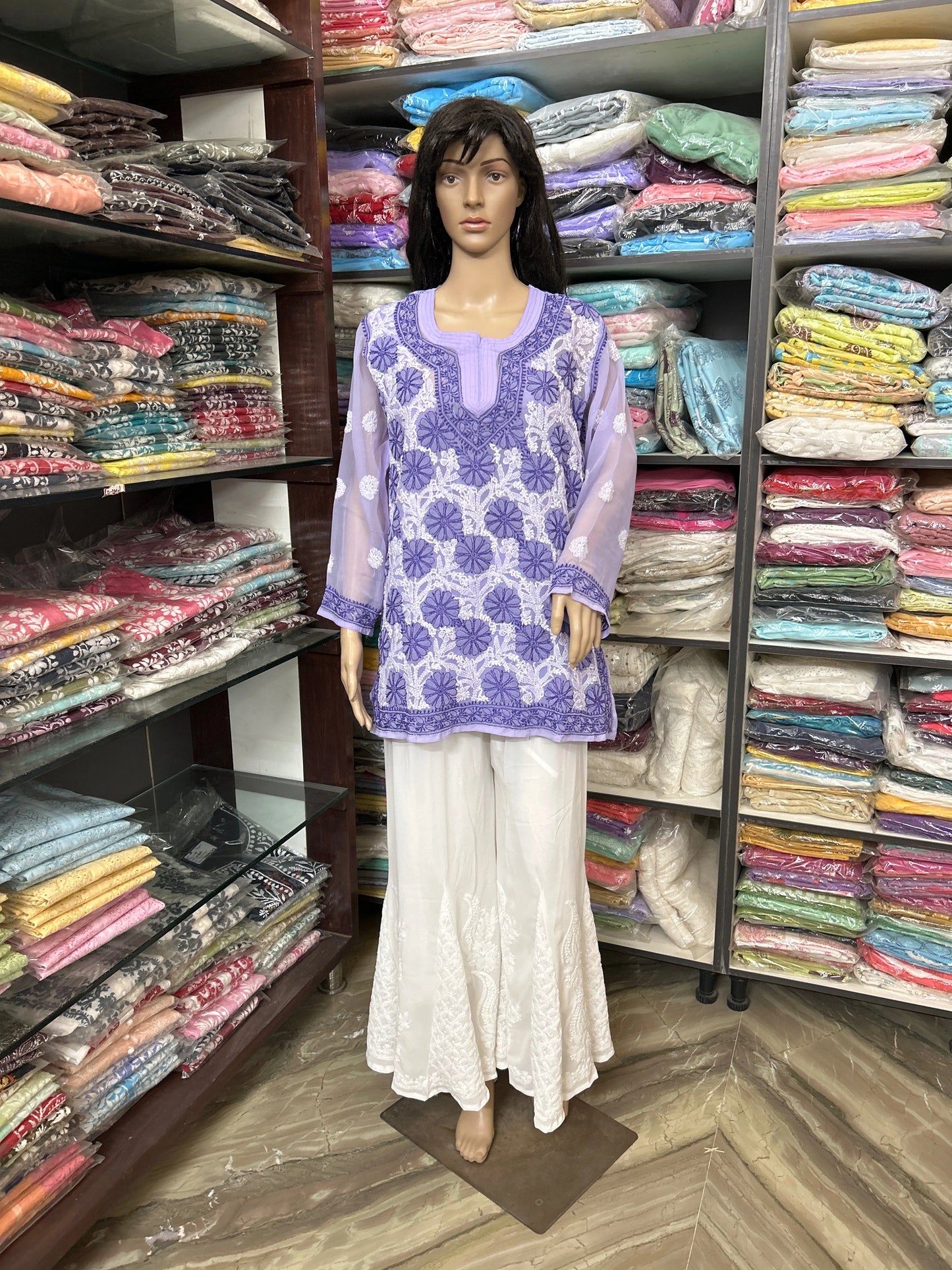 lucknowi chikankari Mannequin wearing a purple floral top and white pants in a fabric store.