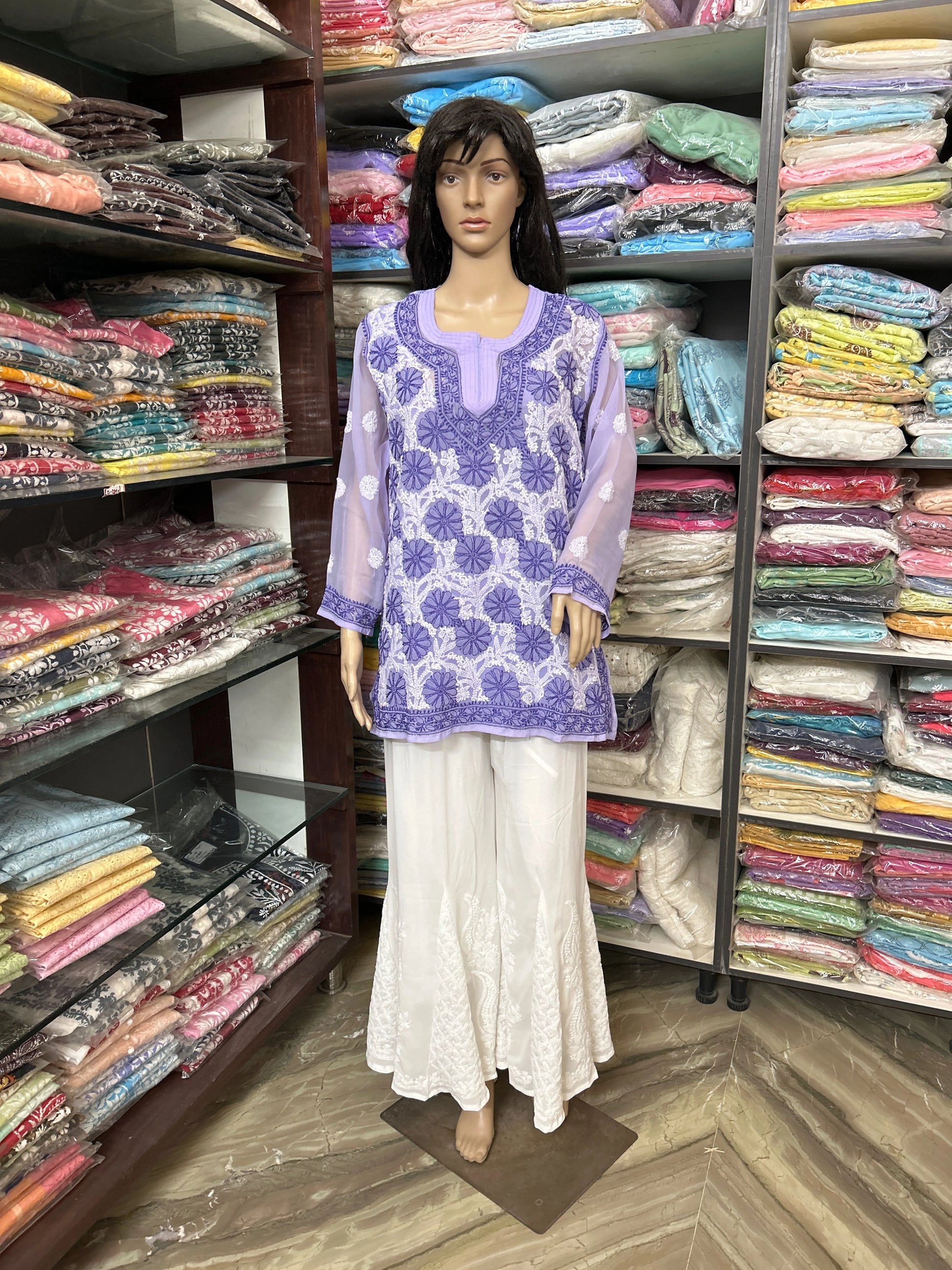 lucknowi chikankari Mannequin wearing a purple floral top and white pants in a fabric store.