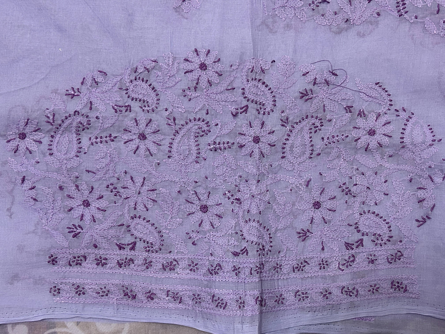 Embroidered fabric with purple floral patterns on a light purple background