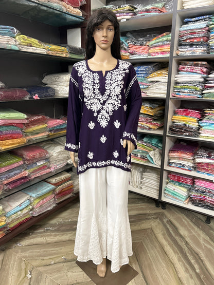 Mannequin wearing a purple embroidered top and white pants in a fabric store.
