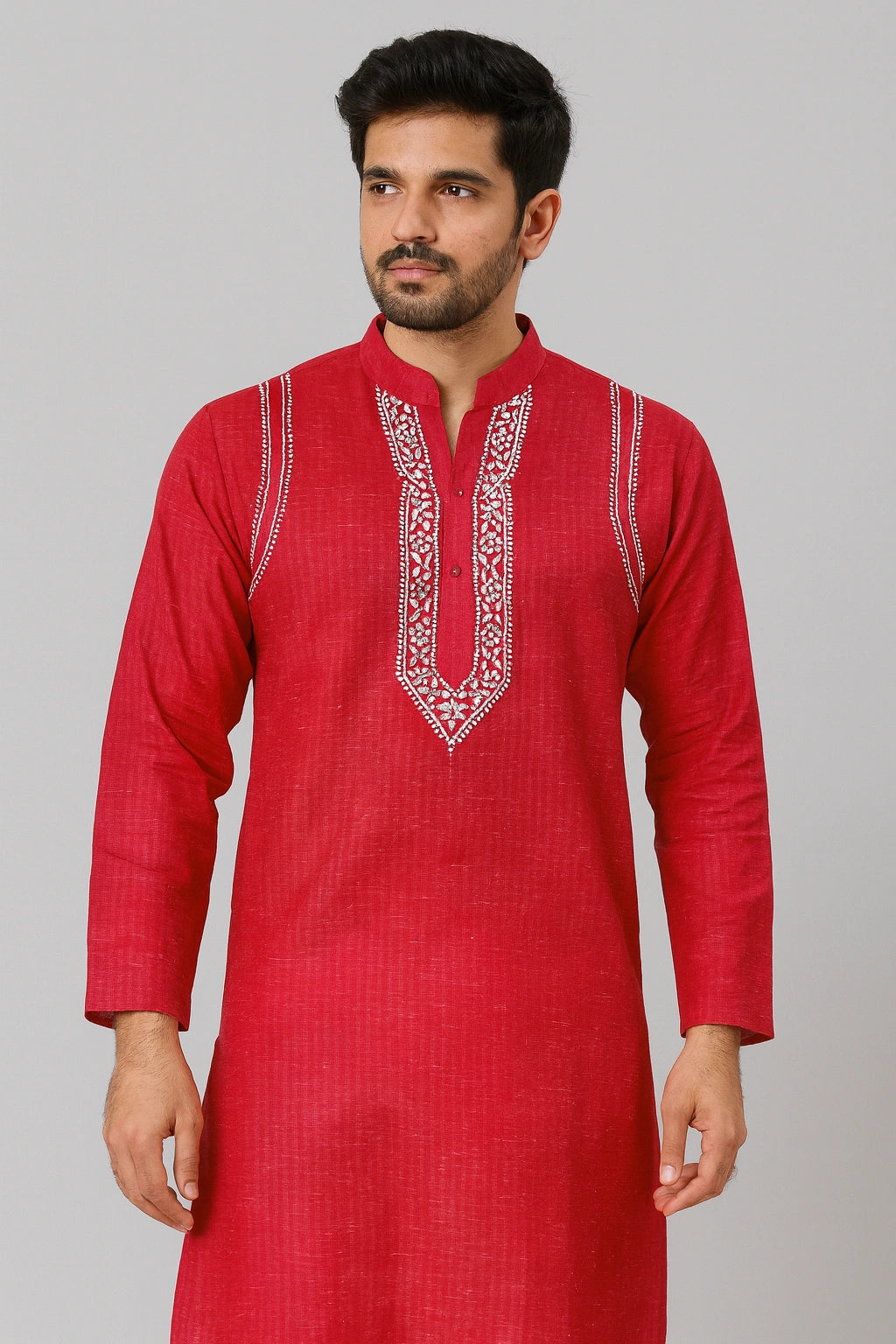Man wearing a red kurta with white embroidery on a gray background